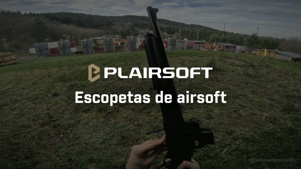 Vista en primera persona de una escopeta de airsoft Tokyo Marui M870 con visor holográfico, sujeta en vertical sobre la hierba de un campo de airsoft con barricadas de bidones al fondo