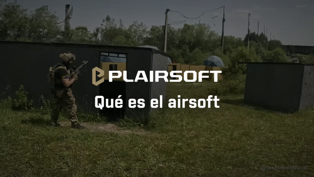 Jugador de airsoft con casco y portaplacas, con el fusil en las manos, pasando junto a una caseta negra en el campo de Soldados de Juguete, en Bizkaia, con más casetas, muros amarillos y cúpulas al fondo