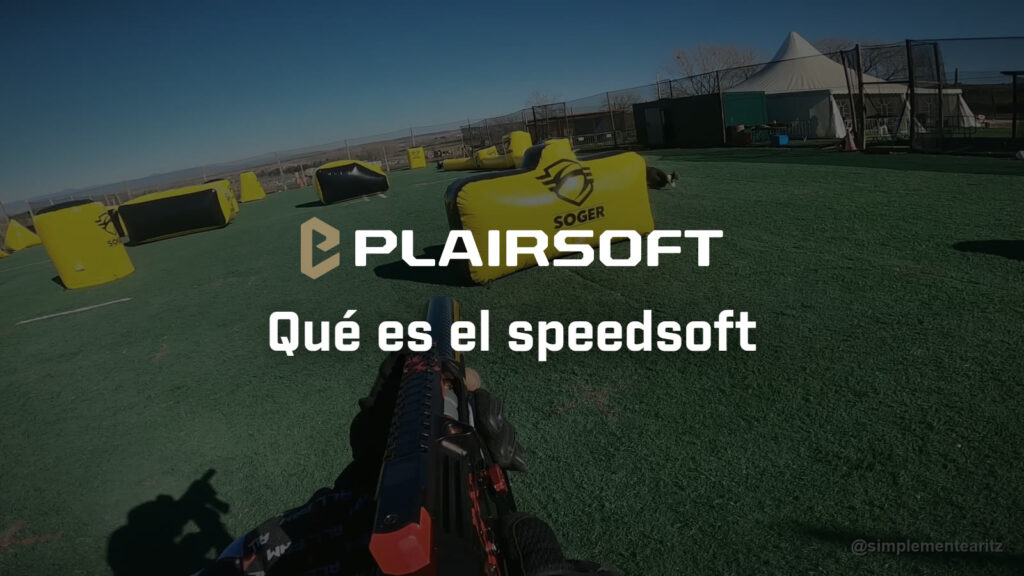 Vista en primera persona de un partido de speedsoft: réplica en mano y campo de césped artificial con obstáculos hinchables amarillos y negros