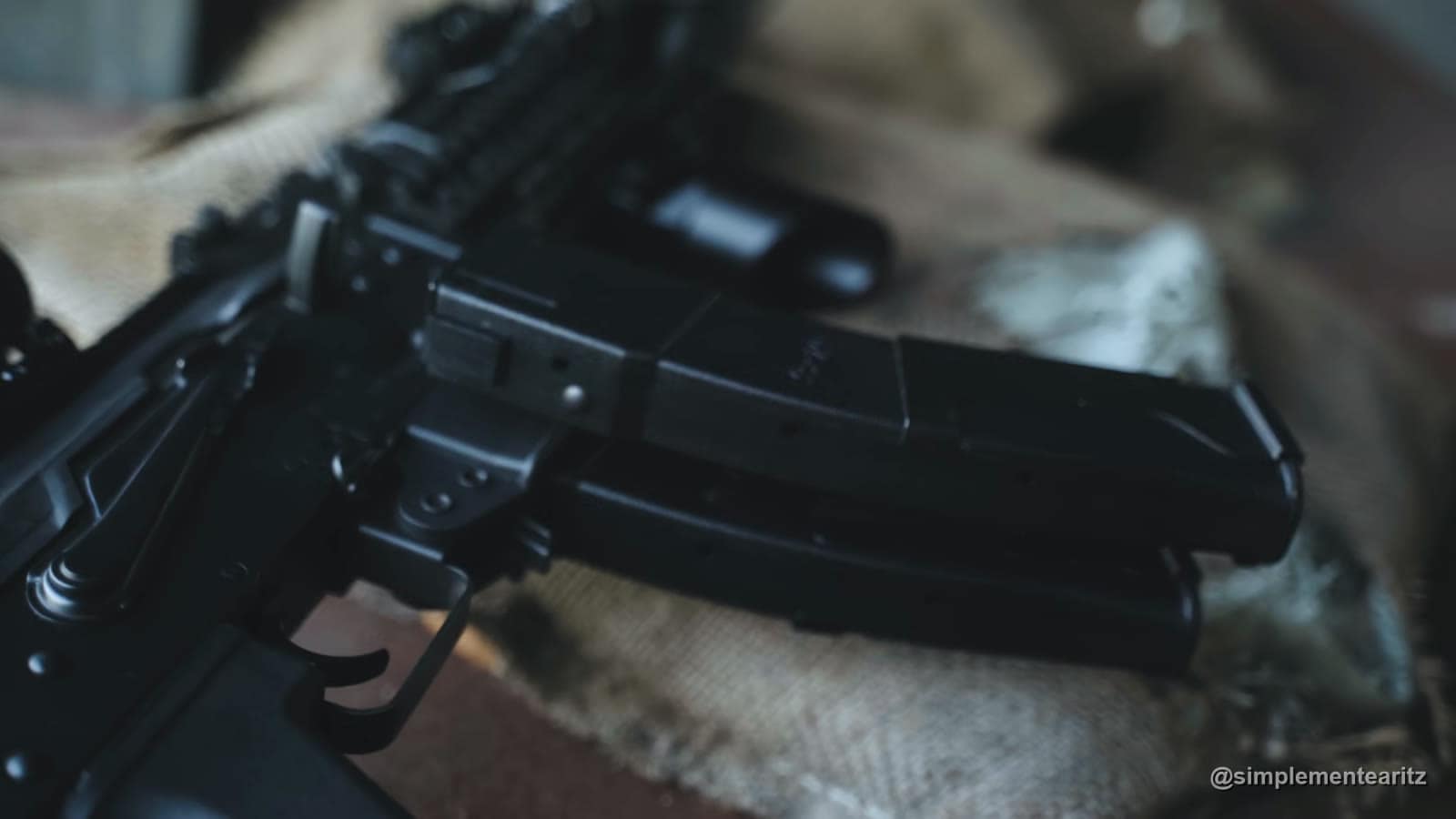 Cargador doble de la Vityaz de LCT, dos cargadores de 9 mm unidos por una pinza metálica, metidos en la réplica y apoyados sobre una tela de camuflaje