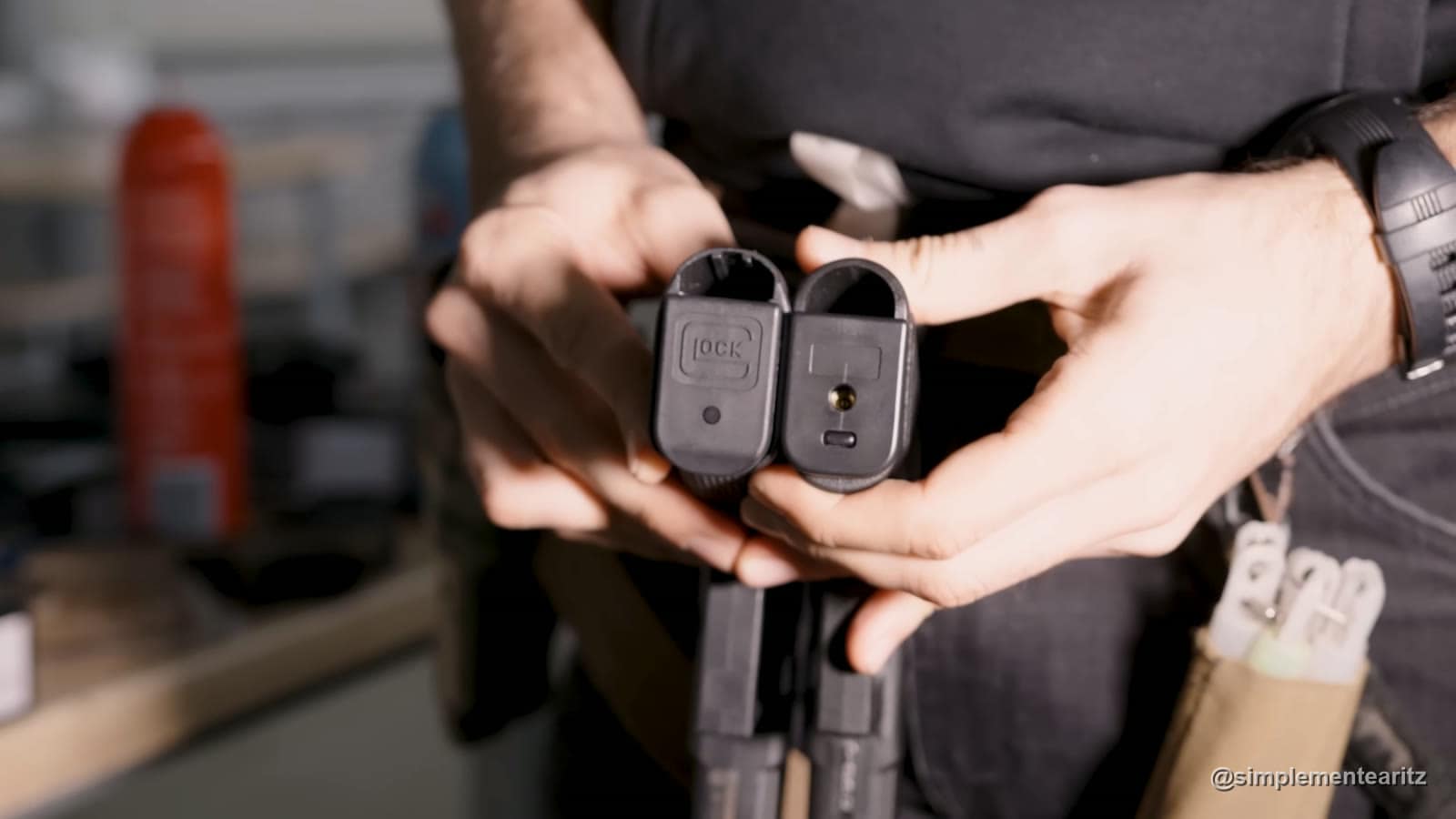 Bases de los cargadores de la Glock 17 Gen5 de VFC, con el logo de Glock grabado, y de la G23 de Saigo, sin marcajes y con la válvula de carga de gas a la vista, sujetas con las manos