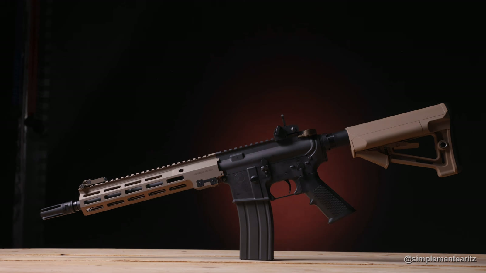 Tokyo Marui URG-I MWS con guardamanos y culata color arena, de pie sobre una mesa de madera con fondo oscuro