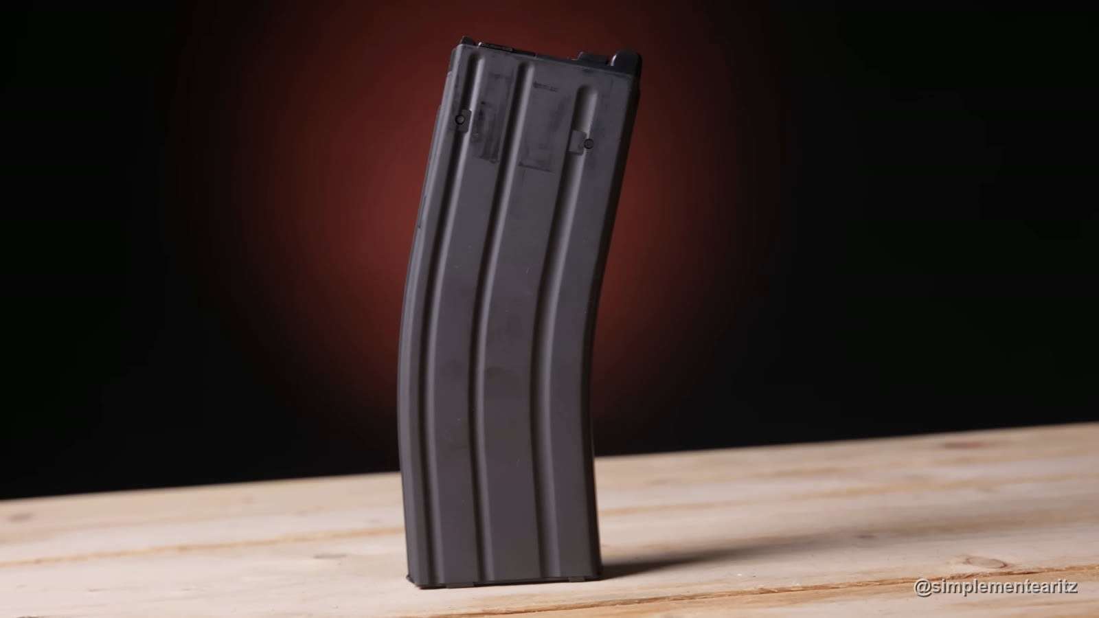 Cargador original de gas de la Tokyo Marui MWS, de pie sobre una mesa de madera con fondo oscuro