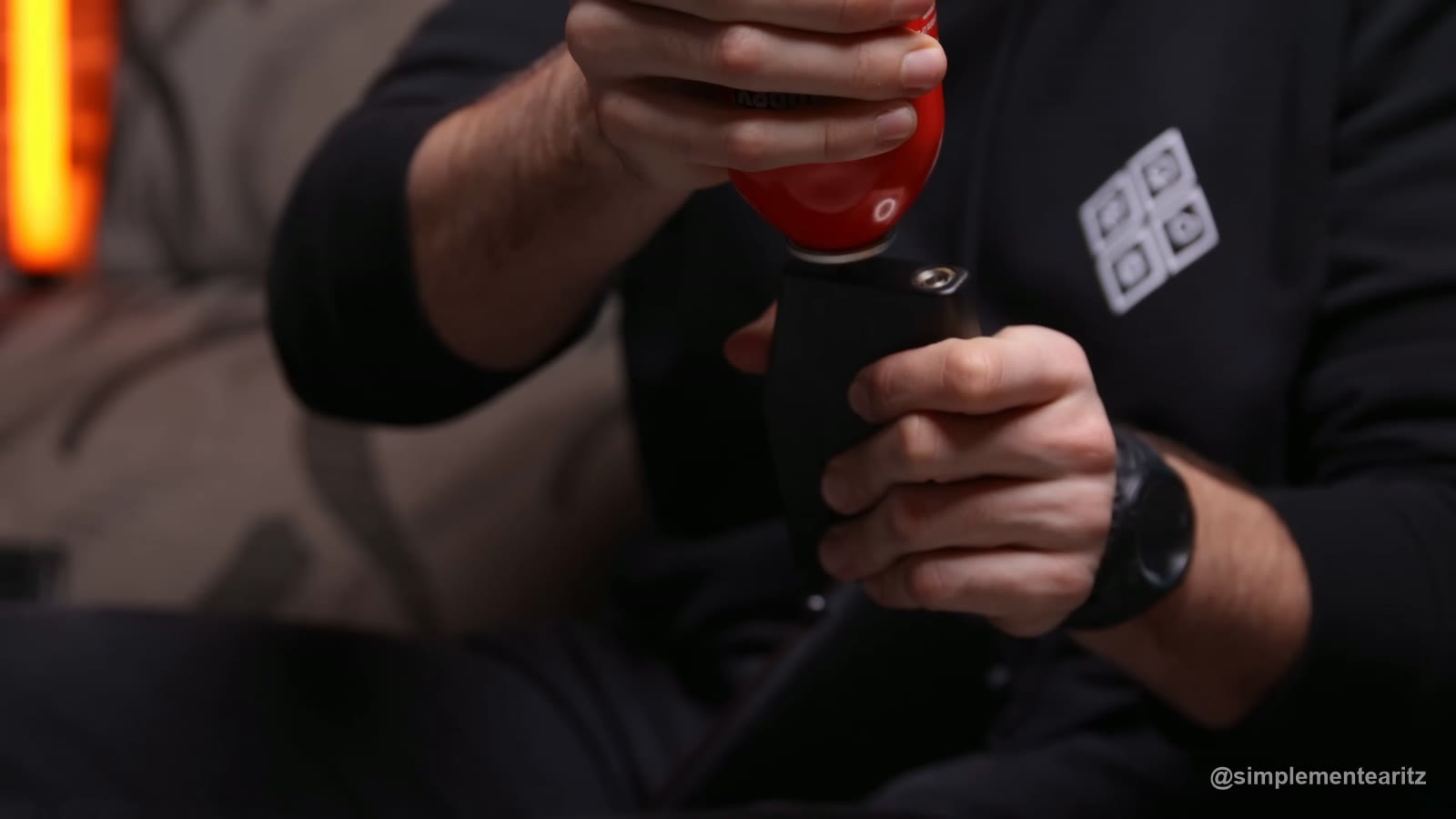Manos rellenando con un bote de gas rojo el depósito de gas extraíble de la escopeta Tokyo Marui M870