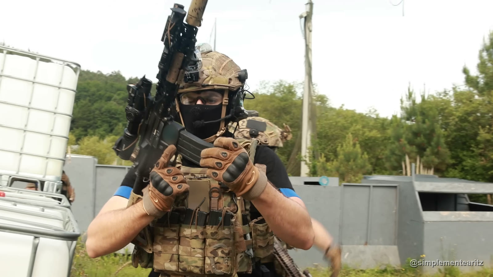 Jugador con casco, gafas y una máscara negra con rejilla delante de la boca, metida en la balaclava, que le tapa nariz, boca y cuello mientras cambia el cargador en una partida