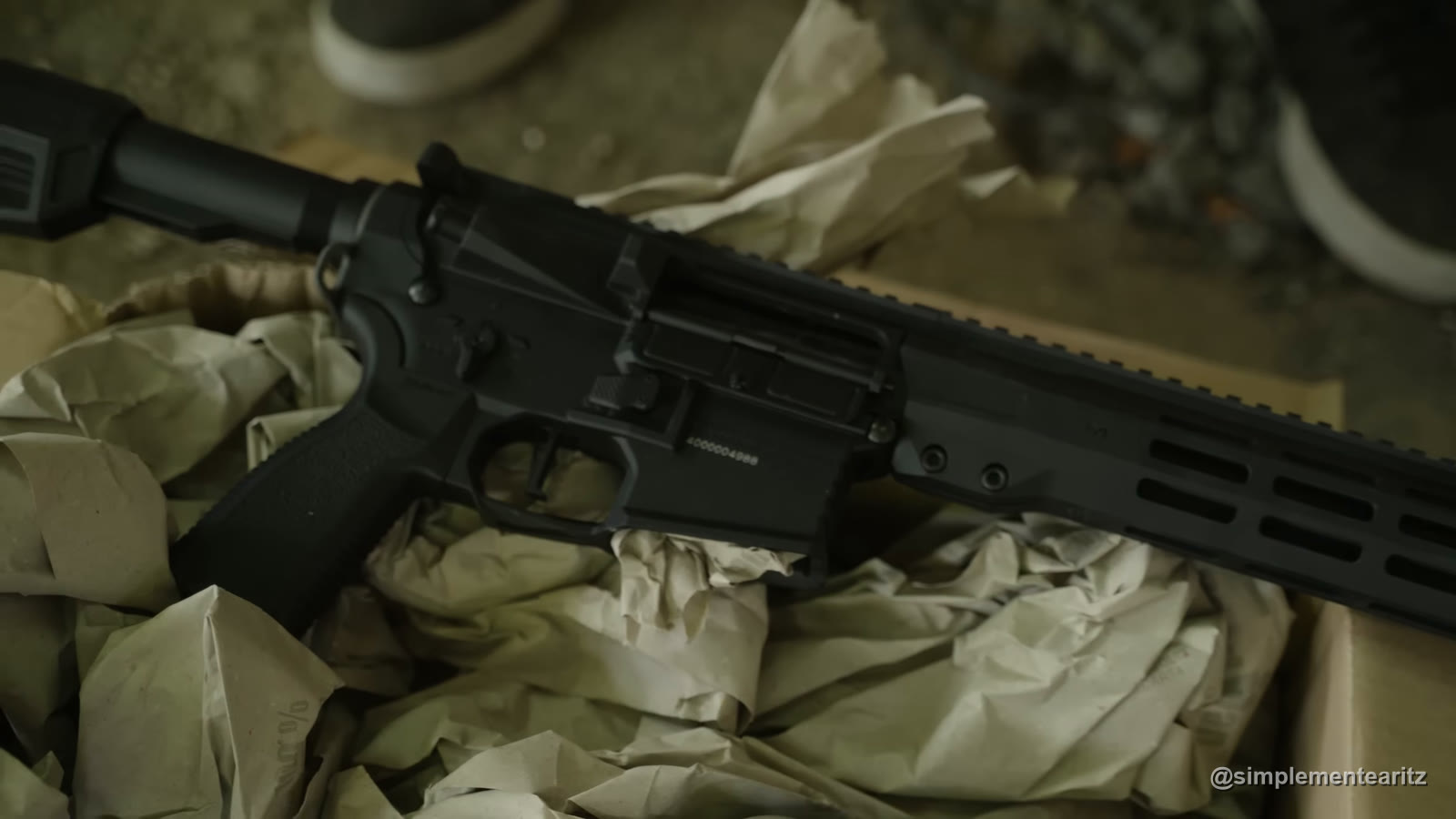 Krytac Trident MK3 negra con guardamanos M-LOK, tumbada sobre una caja de cartón abierta con papel de embalar, antes de pintarla