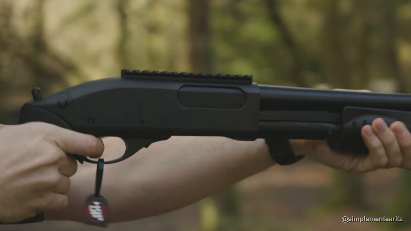 Escopeta de gas M870 Breacher de Tokyo Marui, con raíl en el cajón, empuñada con las dos manos en un claro de bosque