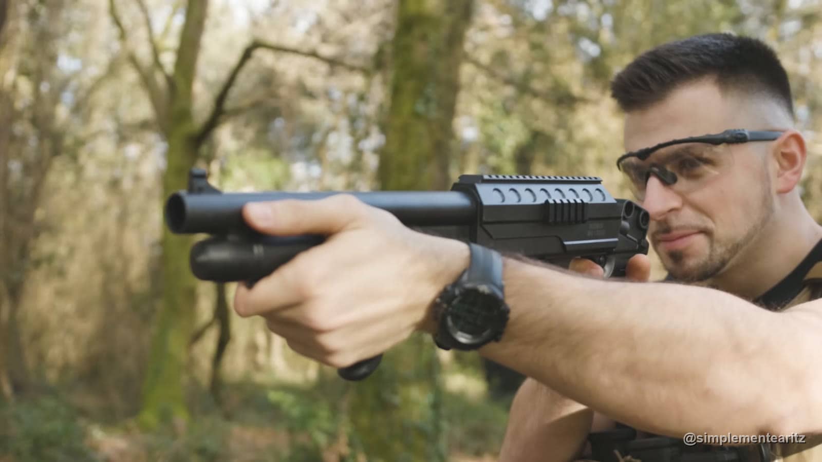 Aritz con gafas de protección apuntando una escopeta de airsoft de muelle de plástico, de las más baratas de la prueba, en un bosque