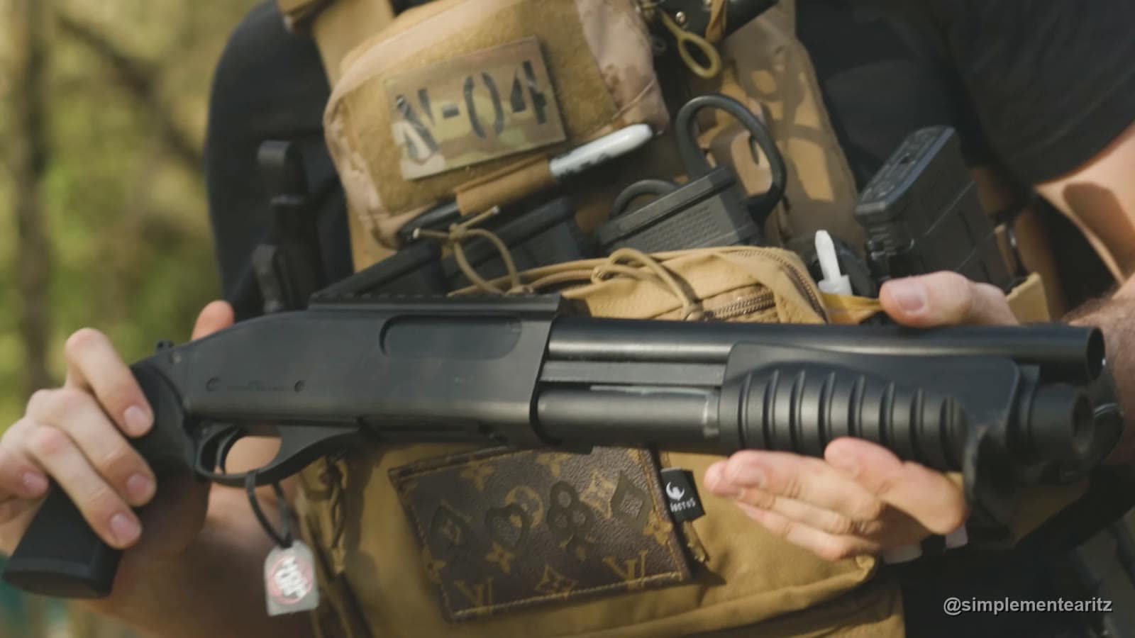 Escopeta de airsoft Tokyo Marui M870 Breacher, corta y sin culata, sujeta a la altura de una placa portadora color arena