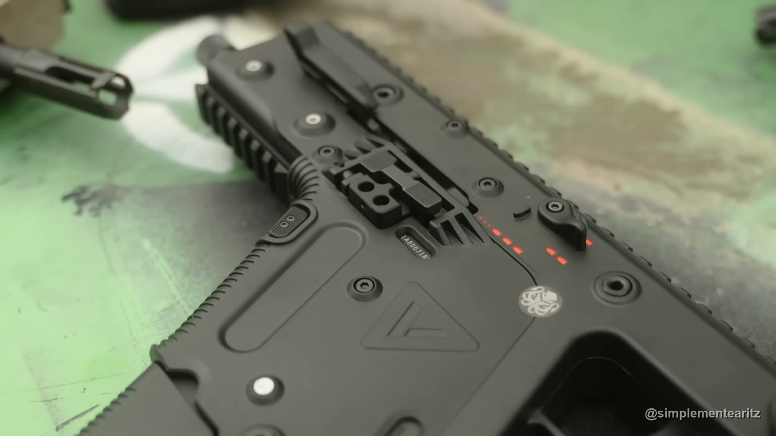 Detalle del cajón de una KRISS Vector de Krytac en negro, con el triángulo de KRISS, el logo del pulpo de Krytac y las marcas rojas del selector de tiro