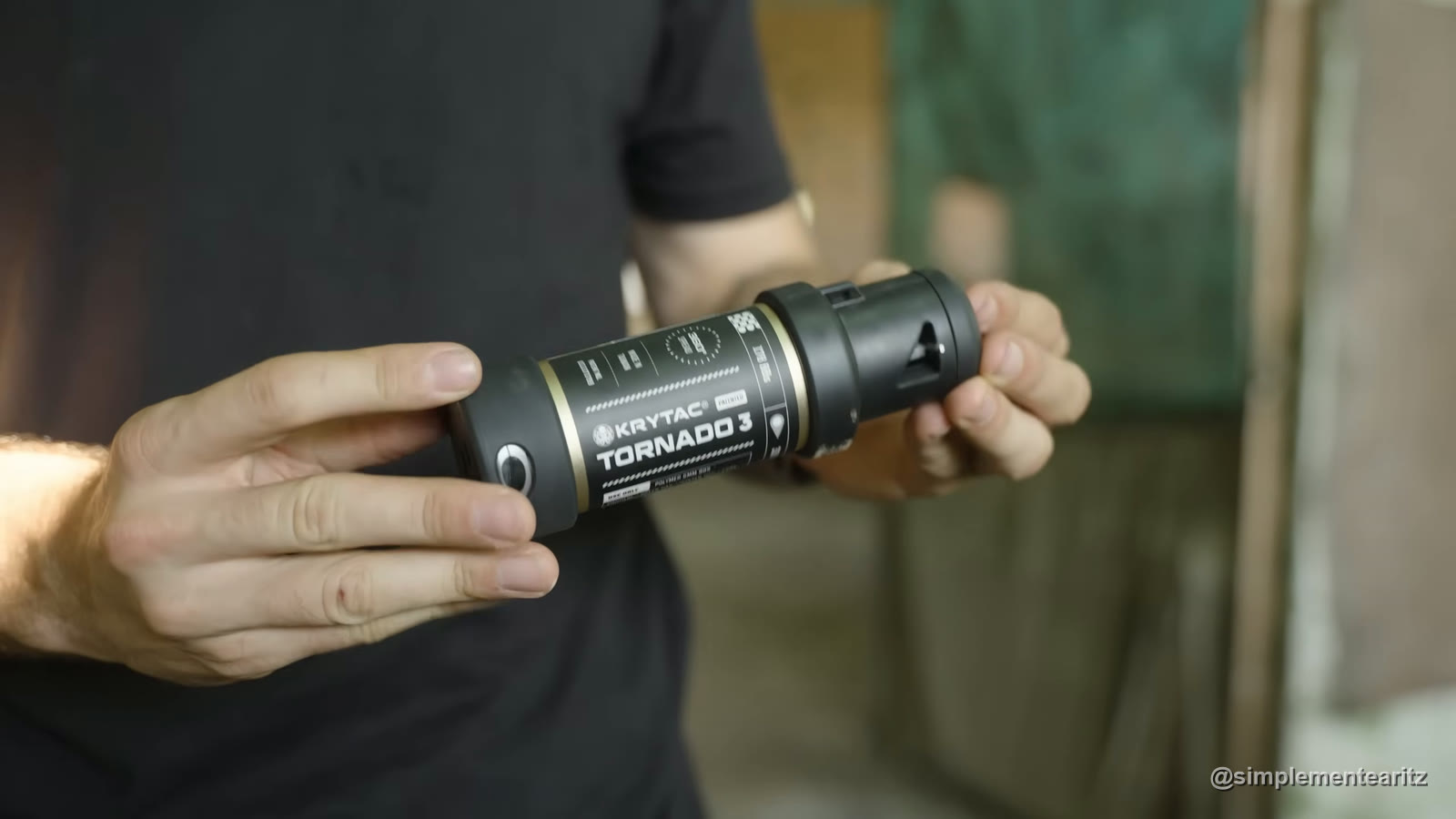 Granada de gas Krytac Tornado 3 negra, con su nombre en la etiqueta, sujeta con las dos manos